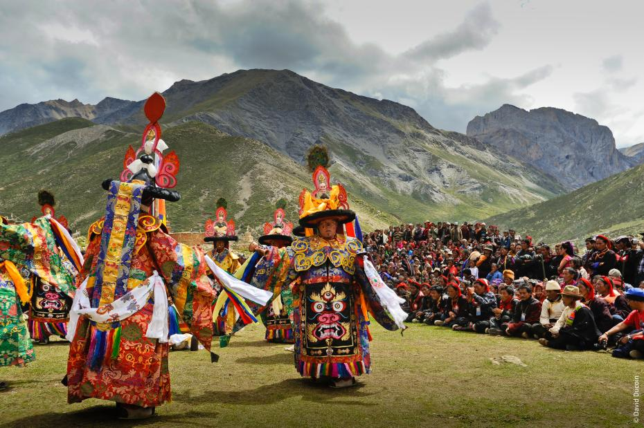 Fête traditionnelle sur les hauts plateaux tibétains, danseurs masqués devant les montagnes